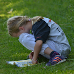 dziewczynka czytająca książkę na polanie