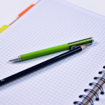 pióro i ołówek leżące na otwartym notesie